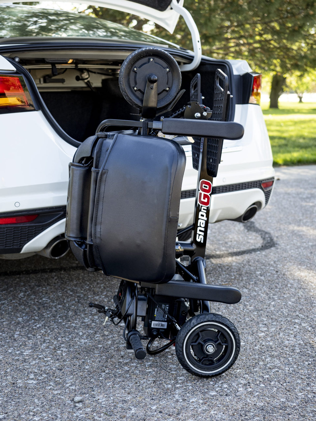 Lightweight SNAPnGO electric mobility scooter folded beside a car for easy loading